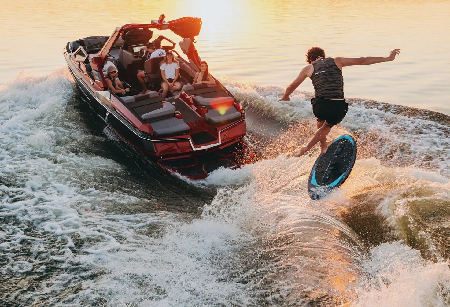 Wakesurfeur sur la vague d’un MasterCraft X22 rouge au coucher du soleil