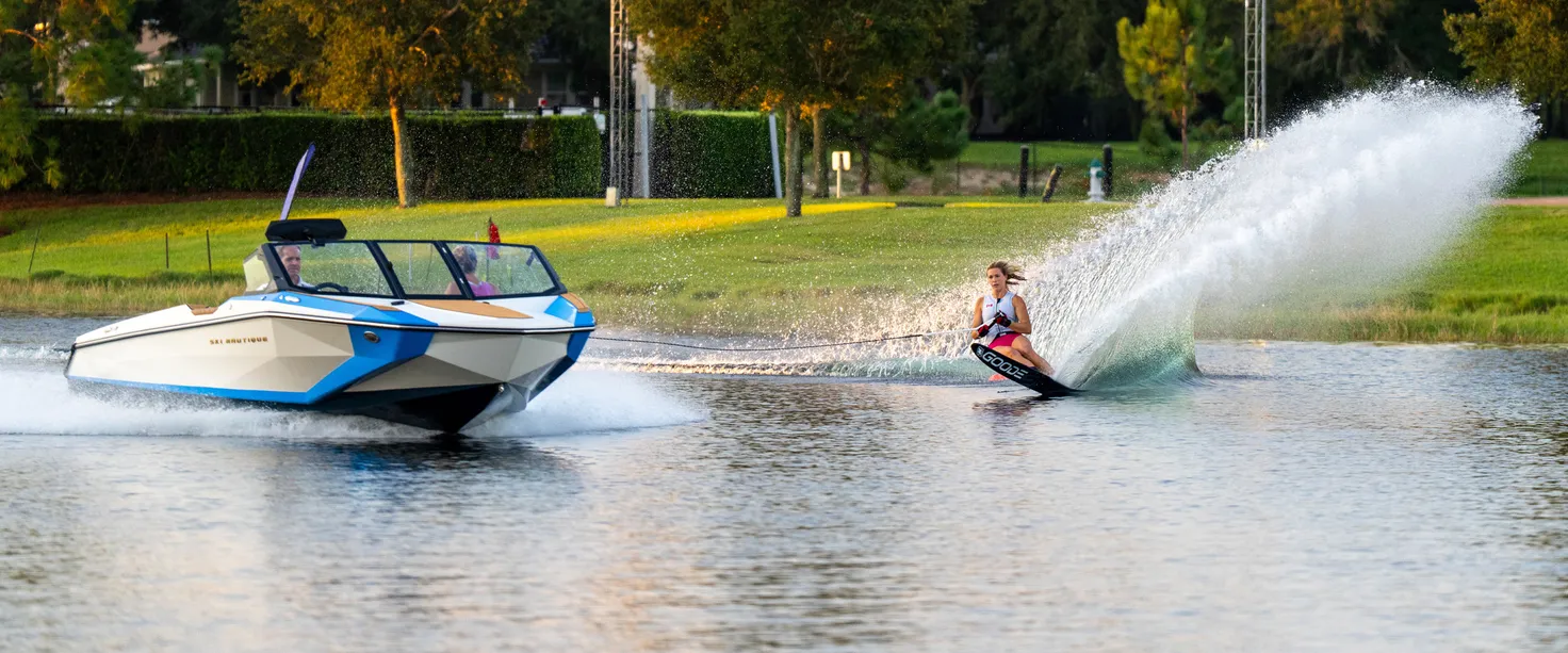 Skieur de slalom en appui derrière un Ski Nautique, gerbe d’eau dans le virage